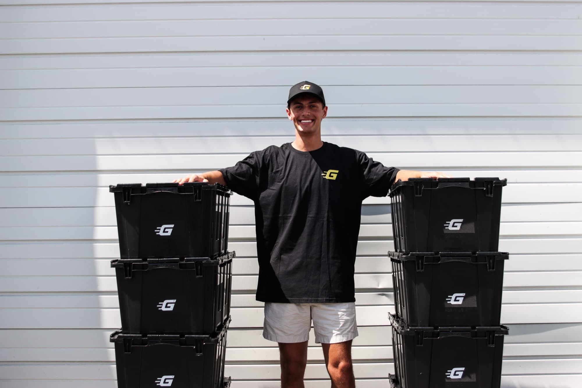 Ghatt2Go's founder standing between two stacks of black rental bins